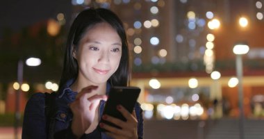 Geceleri cep telefonu kullanan genç bir kadın. 