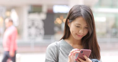 Kadın dışarıda cep telefonuyla çalışıyor. 