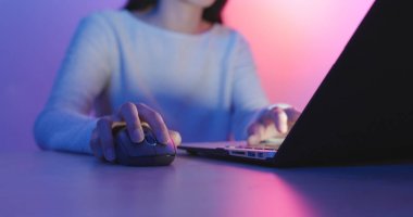 Kadın oynamak oyun dizüstü bilgisayarla iletişim mor ve mavi ışık