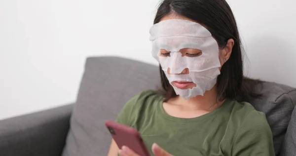 Perempuan Menerapkan Masker Wajah Dan Menggunakan Ponsel Rumah — Stok Foto