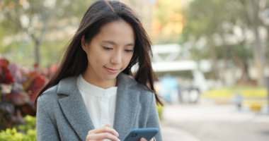 Kadın dışarıda cep telefonuyla çalışıyor. 