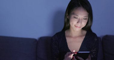 Evde cep telefonu kullanan bir kadın 