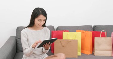 Tablet bilgisayar ile lots-in alışveriş torbaları evde kullanan kadın 