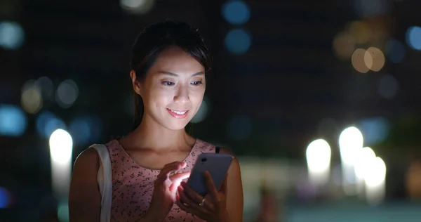 Woman use of mobile phone at night and standing at outdoor