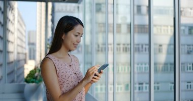 Kadın cep telefonu kullanıyor ve alışveriş merkezinde duruyor.