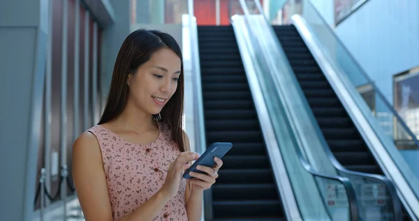 Frau benutzt Handy und steht im Einkaufszentrum — Stockfoto