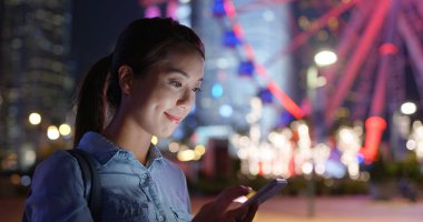 Kadın geceleri şehir içinde hareket eden telefon bakmak