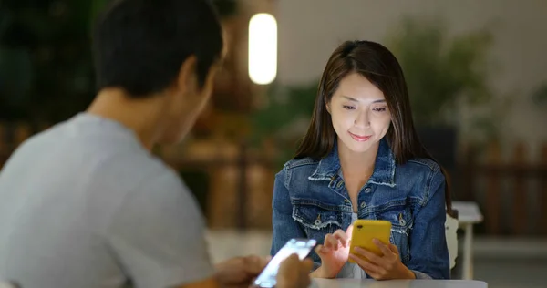 Uso en pareja del teléfono móvil en la cafetería al aire libre por la noche —  Fotos de Stock