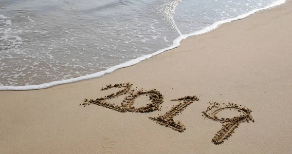 Número 2019 en la playa de arena para el concepto de año nuevo — Foto de Stock