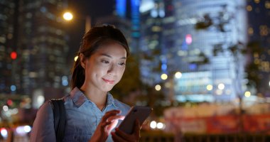 Kadın gece taksi çağırmak için cep telefonu uygulaması kullanıyor.