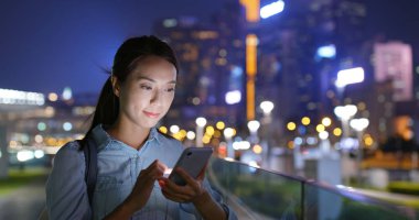 Kadın geceleri cep telefonuna bakar.