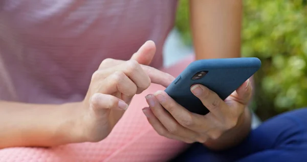 Frau benutzt Handy mit Yogamatte im Freien — Stockfoto