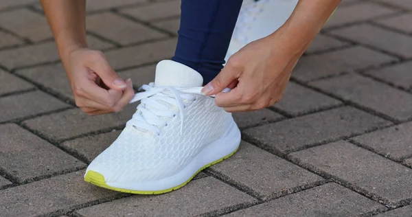 Mladá dospělá samice vázání boty krajkové před běh — Stock fotografie