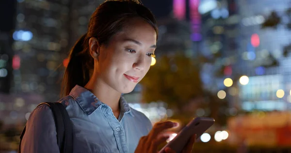 Mujer utilizar el teléfono inteligente en la calle por la noche — Foto de Stock