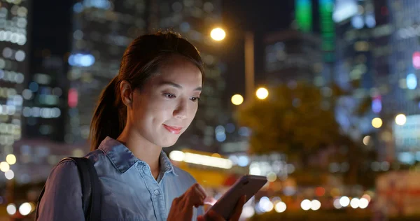 Mujer utilizar el teléfono inteligente en la calle por la noche — Foto de Stock