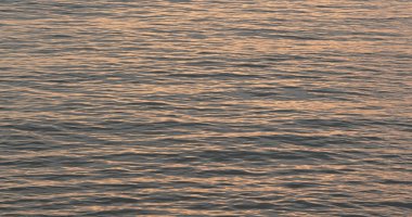 Deniz yüzeyinde gün batımı ışığı