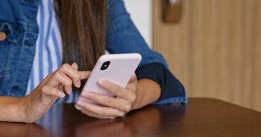Kadın oturma odasında cep telefonu kullanıyor.