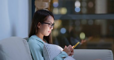 Kadın evde cep telefonuyla çalışıyor.