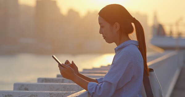 Woman use of cellphone under sunset in Hong Kong