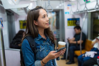 Kadın cep telefonunu tut ve tren kompartımanındaki istasyonu kontrol et.