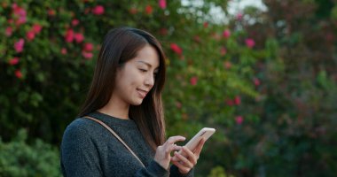 Yeşil arka planda cep telefonu kullanan kadın