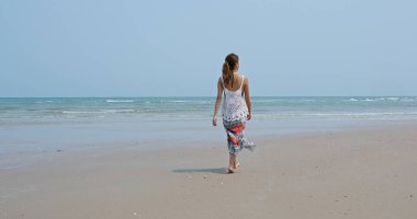 Asyalı kadın sahilde yürüyor.