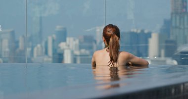 Şehir manzaralı sonsuz yüzme havuzunda bir kadın