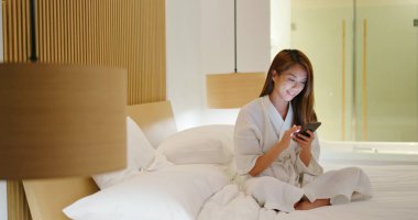 Kadın gece yatakta akıllı telefon kullanıyor.