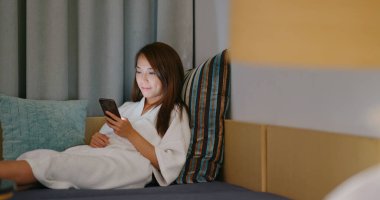 Kadın gece yatakta akıllı telefon kullanıyor.