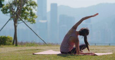 Kadın parkta yoga yapıyor.