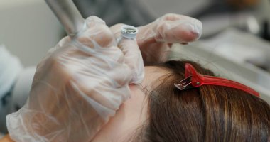 Kadın kaş mikropateni ve kalıcı makyaj yaptırıyor.