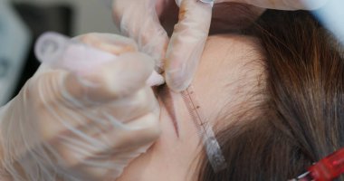 Kadın kaş mikropateni ve kalıcı makyaj yaptırıyor.