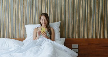 Kadın yatağında cep telefonu kullanıyor