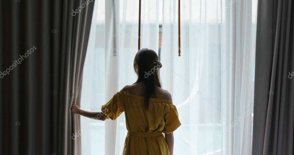 Woman open the curtain at morning