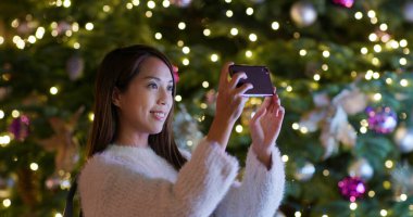 Kadın Noel ağacı süslemesinde fotoğraf çekiyor.