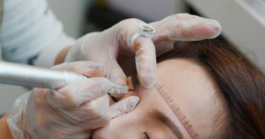 Kadın güzellik salonunda mikro pigmentasyon yaptırıyor.