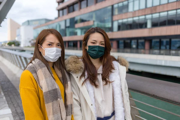 Two woman wear face mask in city