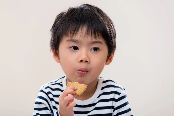 子供の男の子は白い背景にクッキーを食べる — ストック写真