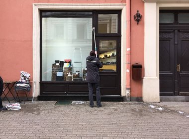 Riga 'da bir işçi kışın bir ayakkabı mağazasının camını siler.