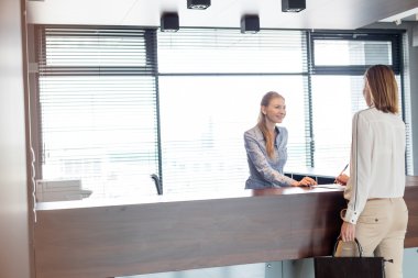 Happy receptionist talking with businesswoman clipart