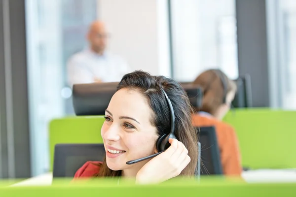 Mooie zakenvrouw hoofdtelefoon gebruiken in office — Stockfoto