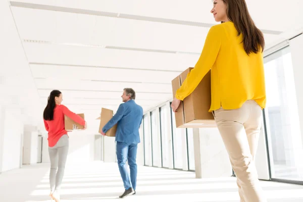 Businesswoman with colleagues carrying cardboard boxes — Stock Photo, Image