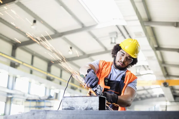 Trabajador usando amoladora en metal en fábrica — Foto de Stock