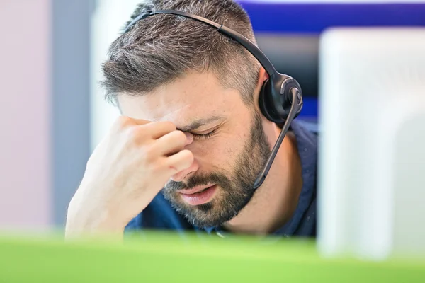 Hombre de negocios cansado con auriculares en la oficina — Foto de Stock