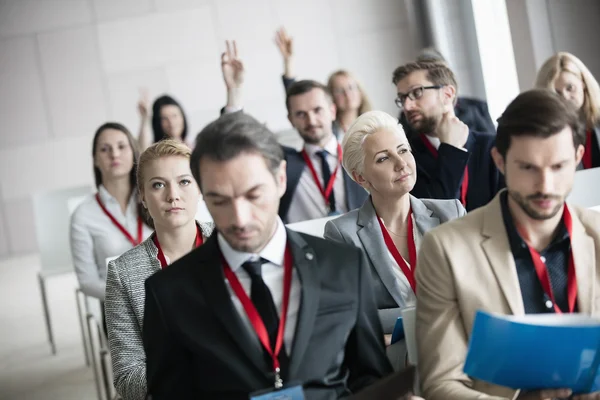 Businesswoman sitting with colleagues in seminar hall — Stock Photo, Image