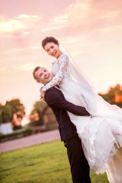 Счастливый жених, несущий невесту на поле — стоковое фото