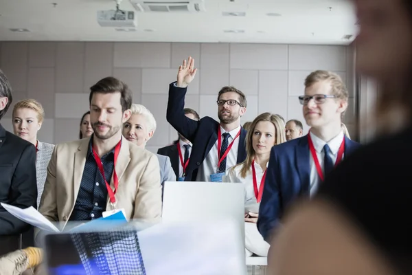 Бизнесмен поднимает руку во время семинара — стоковое фото