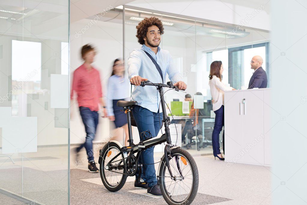 Young businessman walking with bicycle at office 