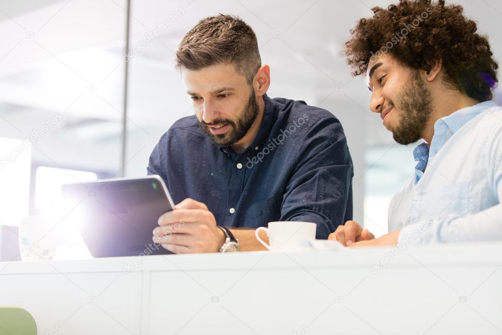 Businessmen using tablet computer in office 