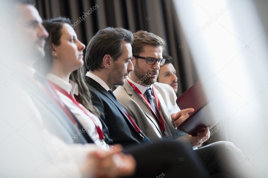 Businessmen discussing over file during seminar 